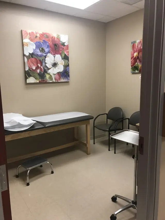 An exam room at Sun Valley Health and Wellness, the treatment table drawn with fresh paper under a painted floral canvas